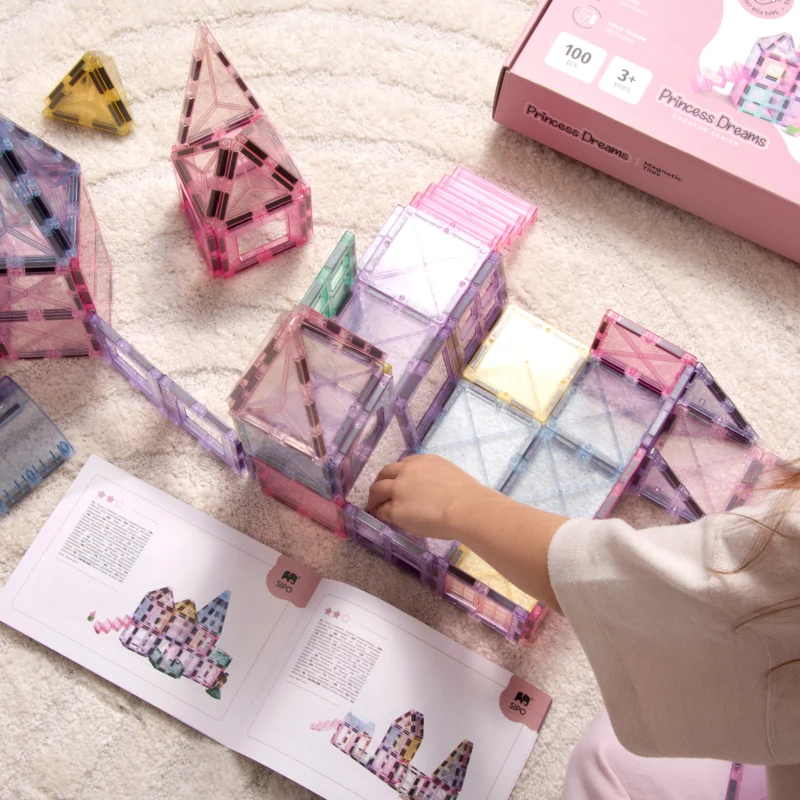 Dziecko buduje zamek SIPO Princess Dreams na dywanie obok otwartego przewodnika budowania.
